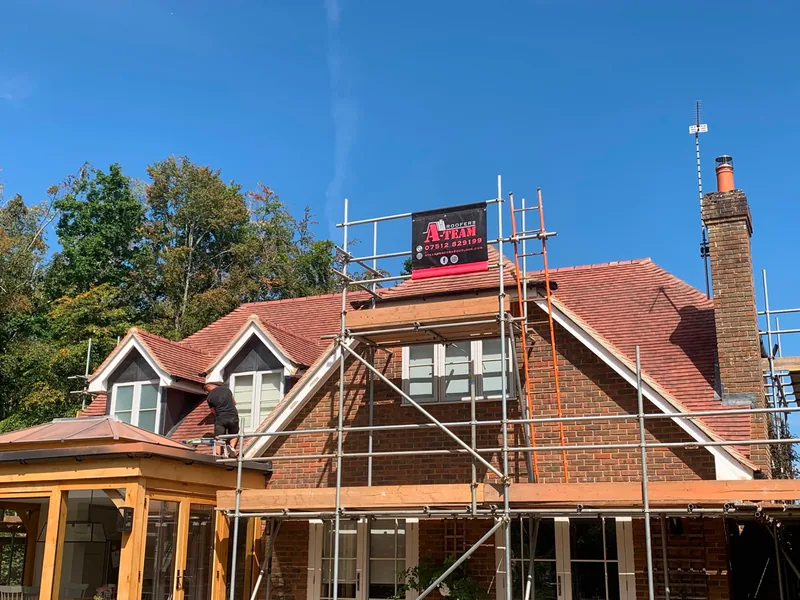 A Team Roofers banner on a scaffolded roof replacement